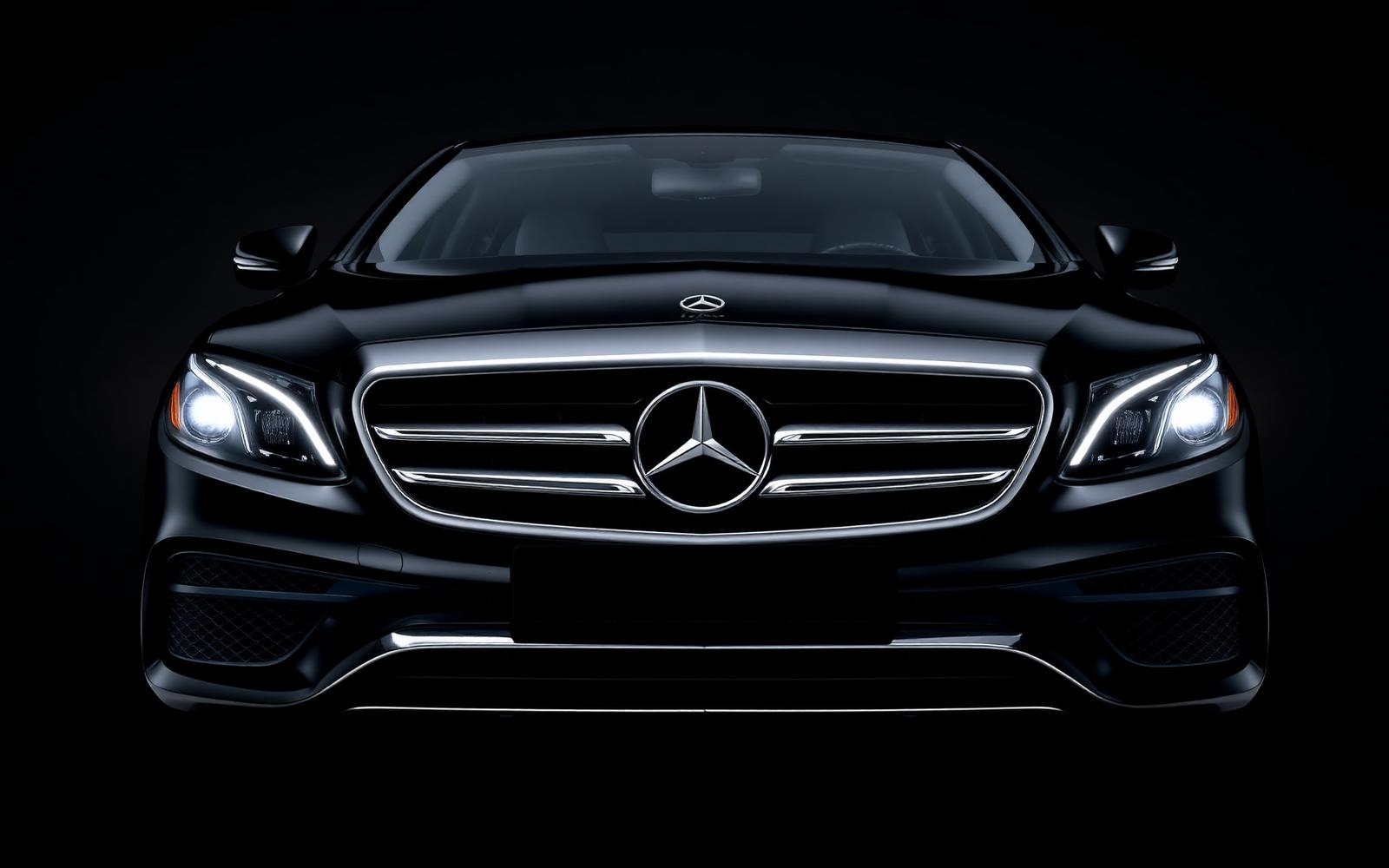 Front-on studio portrait of a black Mercedes-Benz E-Class executive chauffeur sedan with chrome grille and LED headlights
