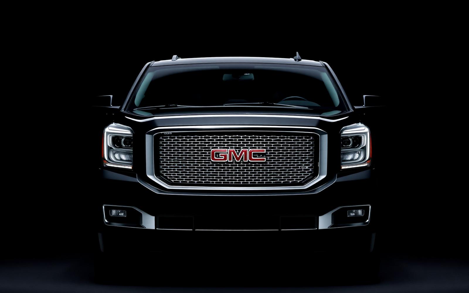 Front studio portrait of a black GMC Yukon Denali full-size luxury SUV with LED matrix headlights and chrome grille