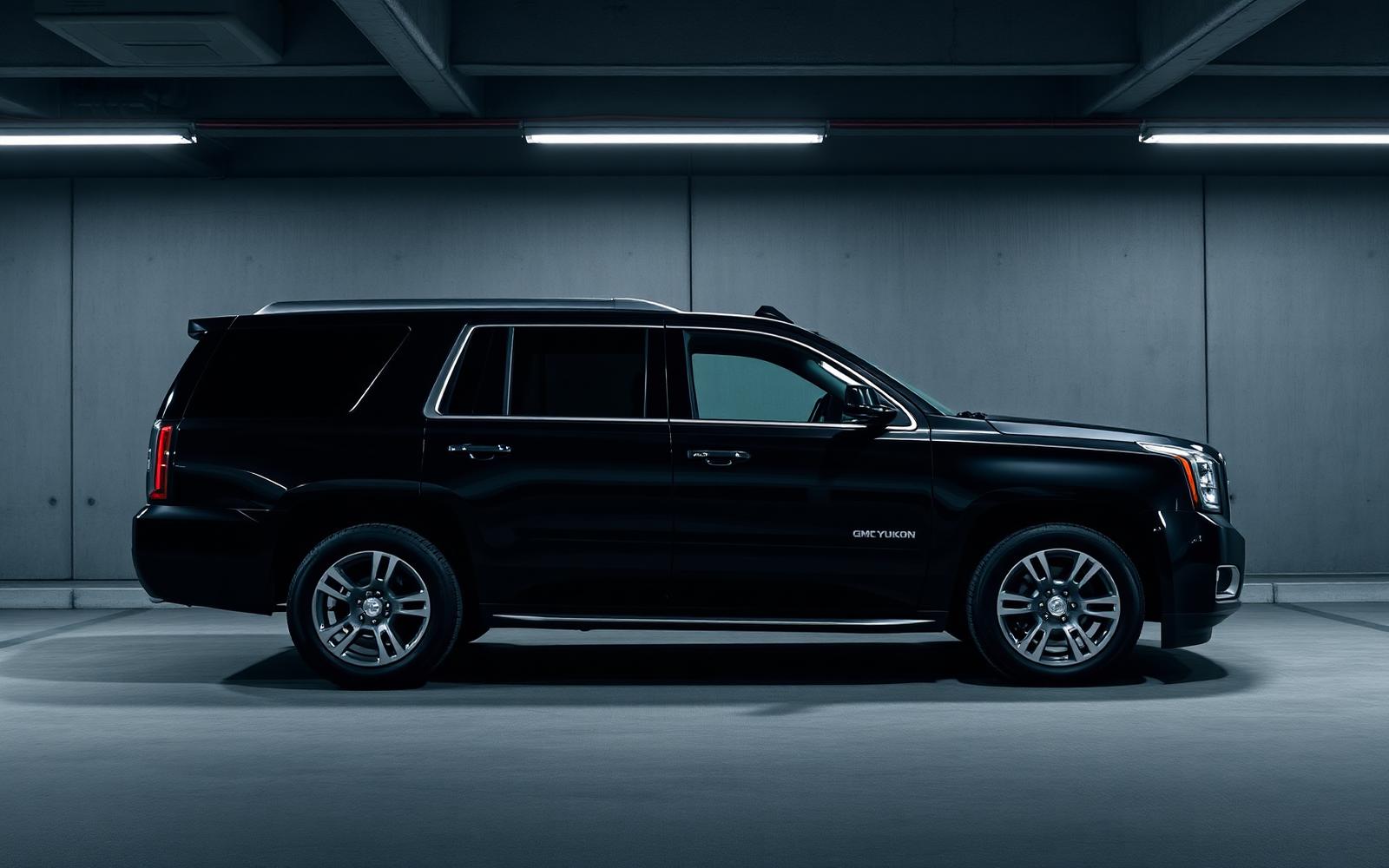 Perfect side profile of a black GMC Yukon Denali luxury SUV against a moody concrete parkade wall