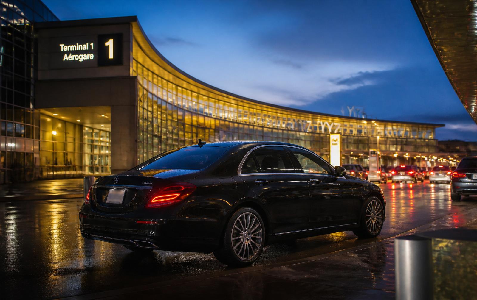 Black Mercedes-Benz sedan at Toronto Pearson Terminal 1 arrivals at dusk